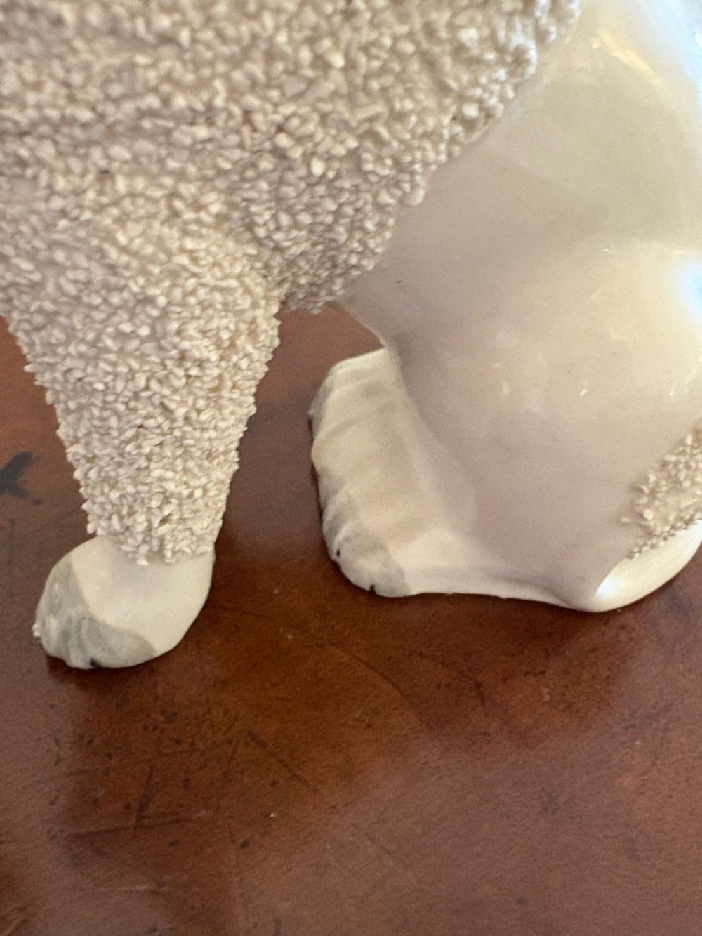 A matching pair of Victorian cream earthenware Staffordshire poodle figurines sitting upright with hand-applied textured fur and gilded collar details. View V