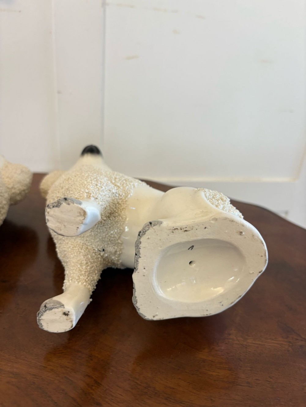 A matching pair of Victorian cream earthenware Staffordshire poodle figurines sitting upright with hand-applied textured fur and gilded collar details. View VI