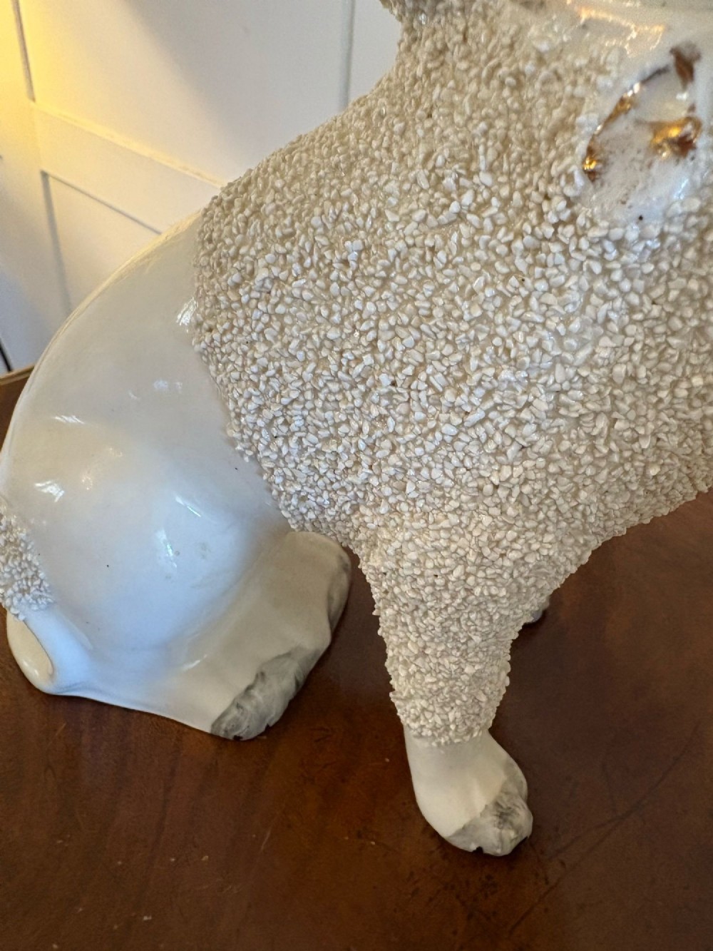 A matching pair of Victorian cream earthenware Staffordshire poodle figurines sitting upright with hand-applied textured fur and gilded collar details. View VII