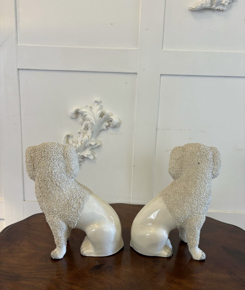 A matching pair of Victorian cream earthenware Staffordshire poodle figurines sitting upright with hand-applied textured fur and gilded collar details. View VIII