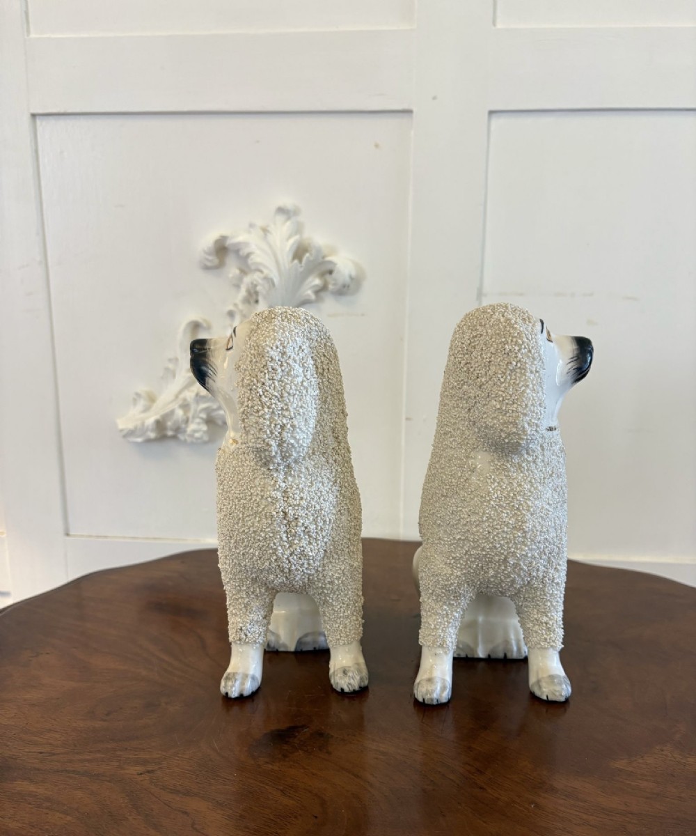 A matching pair of Victorian cream earthenware Staffordshire poodle figurines sitting upright with hand-applied textured fur and gilded collar details. View IX