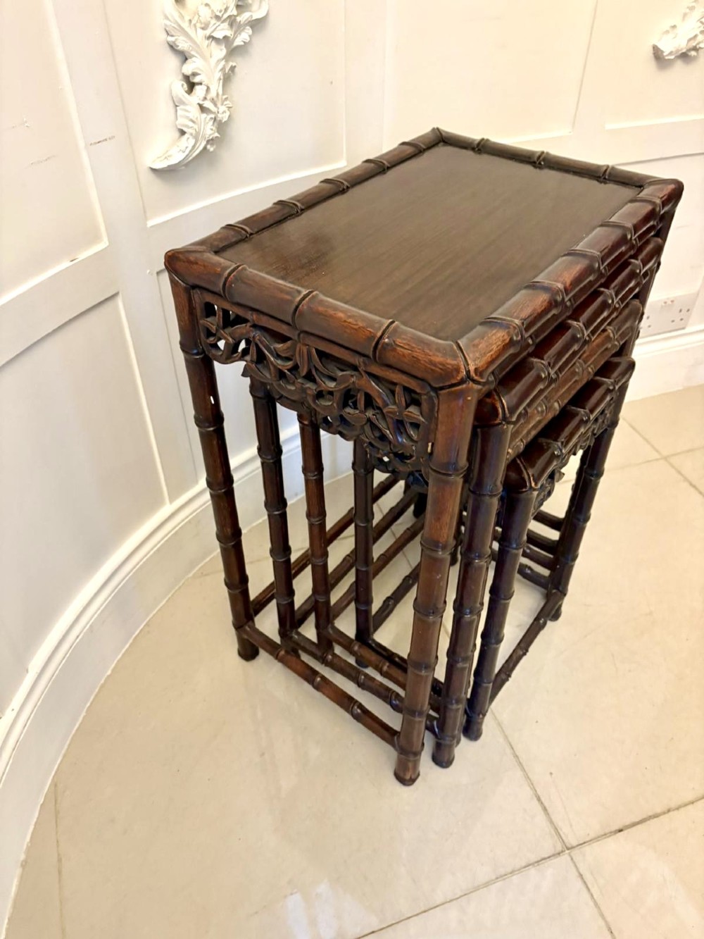 A set of four dark brown carved hardwood nesting tables featuring faux bamboo turnings and openwork carved aprons. View IV