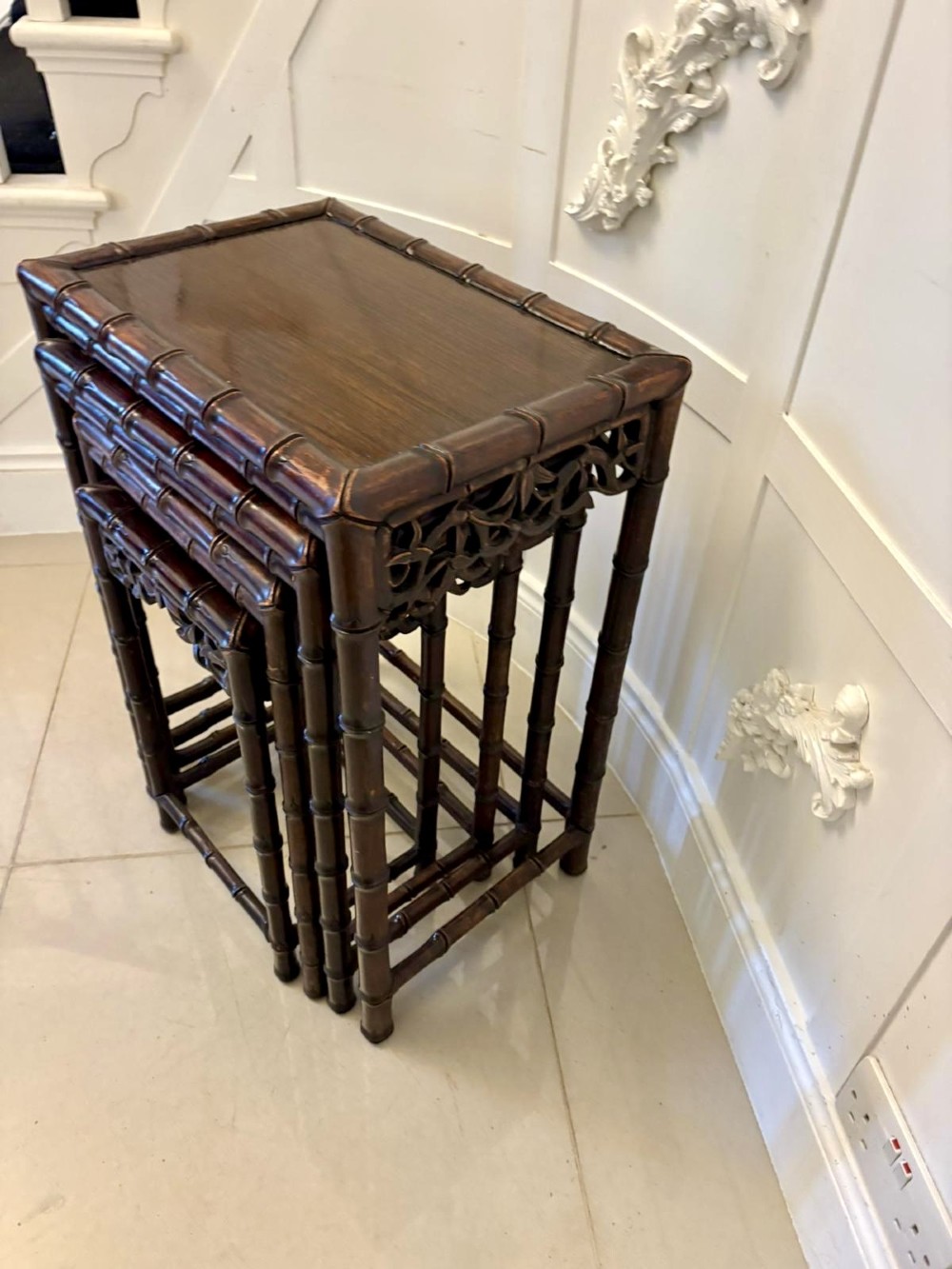 A set of four dark brown carved hardwood nesting tables featuring faux bamboo turnings and openwork carved aprons. View VI