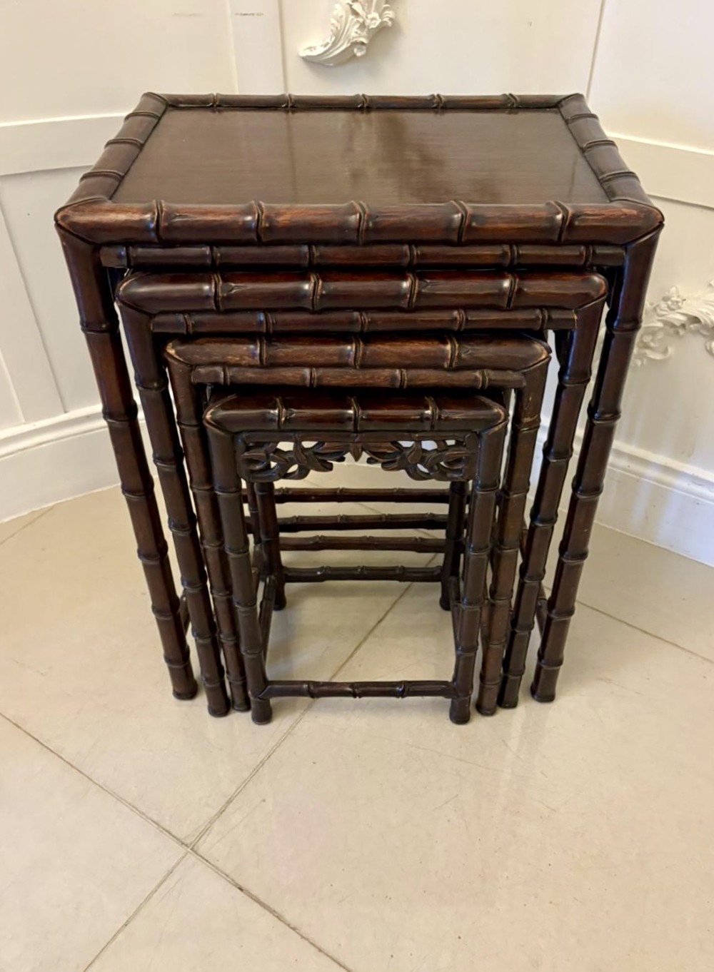 A set of four dark brown carved hardwood nesting tables featuring faux bamboo turnings and openwork carved aprons. View IX