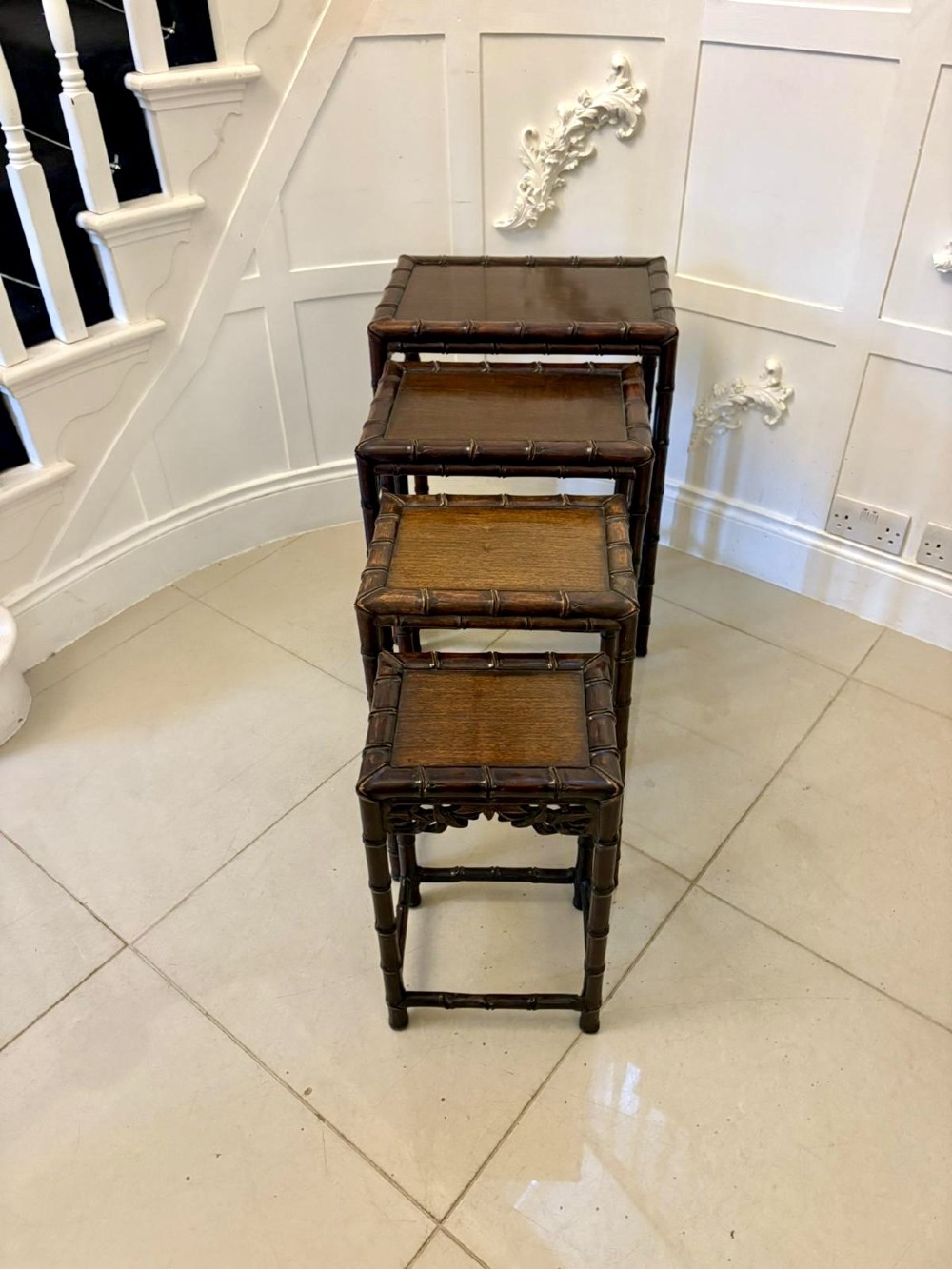 A set of four dark brown carved hardwood nesting tables featuring faux bamboo turnings and openwork carved aprons. View X