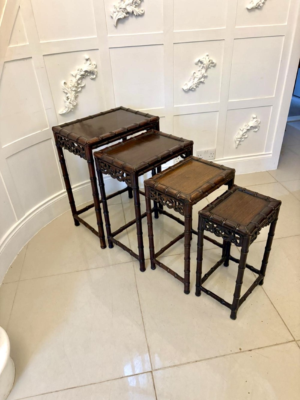 A set of four dark brown carved hardwood nesting tables featuring faux bamboo turnings and openwork carved aprons. View XI