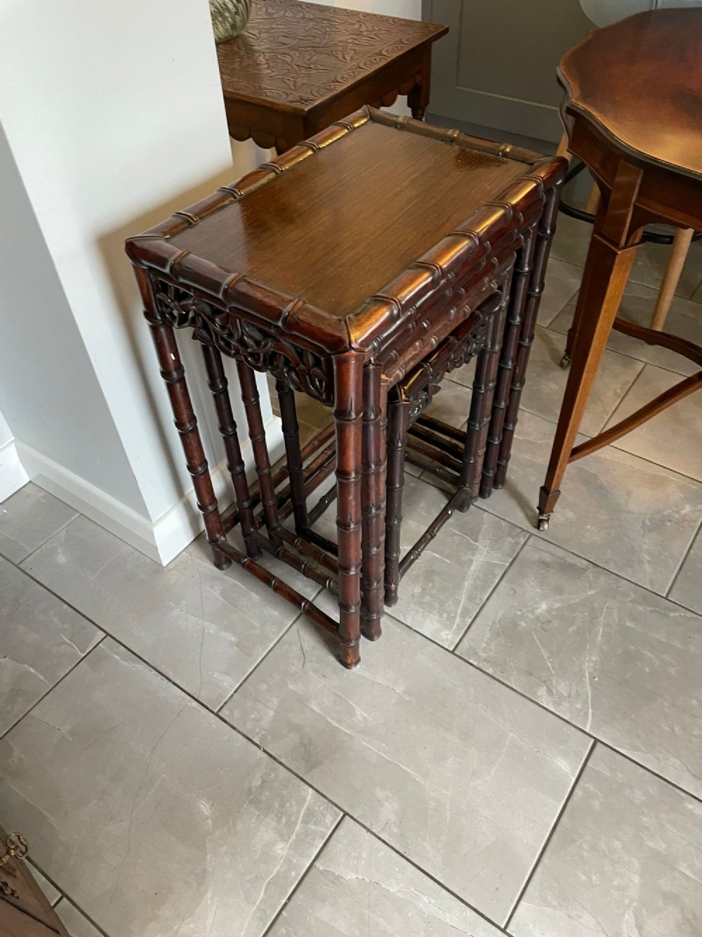 A set of four dark brown carved hardwood nesting tables featuring faux bamboo turnings and openwork carved aprons. View XII