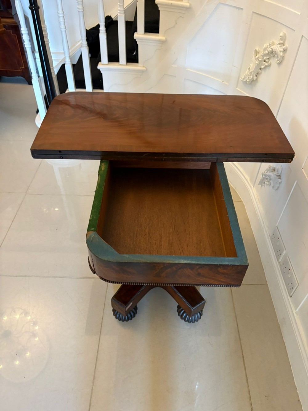 A 19th-century William IV figured mahogany card table with a fold-over top, carved central pedestal, and a concave platform base supported by carved feet. View III