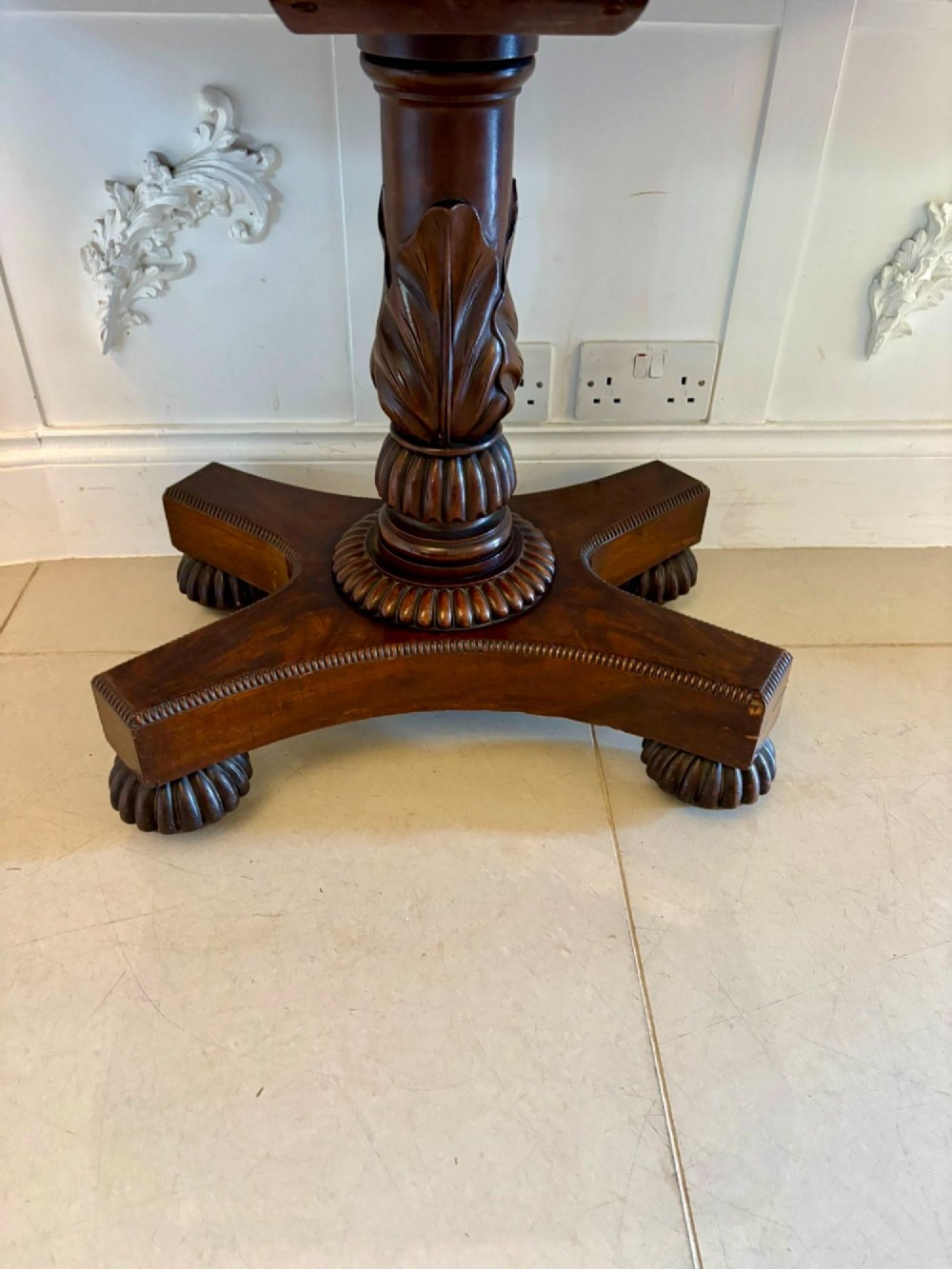 A 19th-century William IV figured mahogany card table with a fold-over top, carved central pedestal, and a concave platform base supported by carved feet. View VII