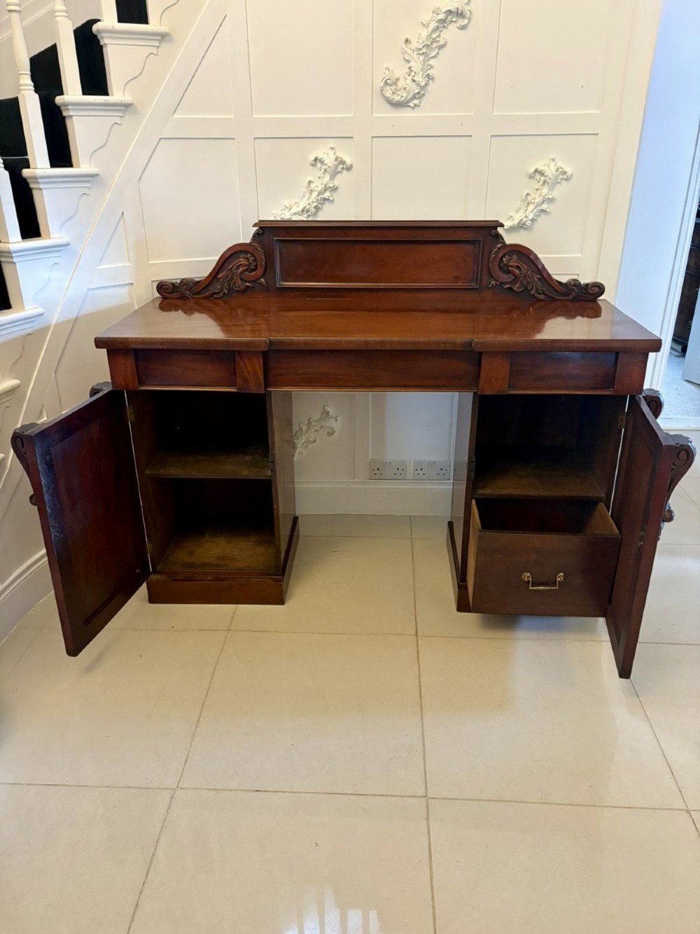 A Victorian mahogany pedestal sideboard featuring a raised backboard with carved scrollwork and two flanking pedestal cupboards. View VIII