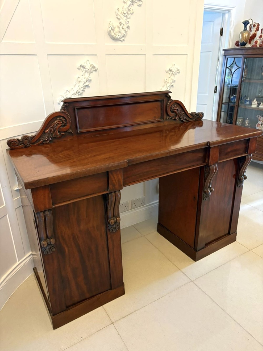 A Victorian mahogany pedestal sideboard featuring a raised backboard with carved scrollwork and two flanking pedestal cupboards. View X