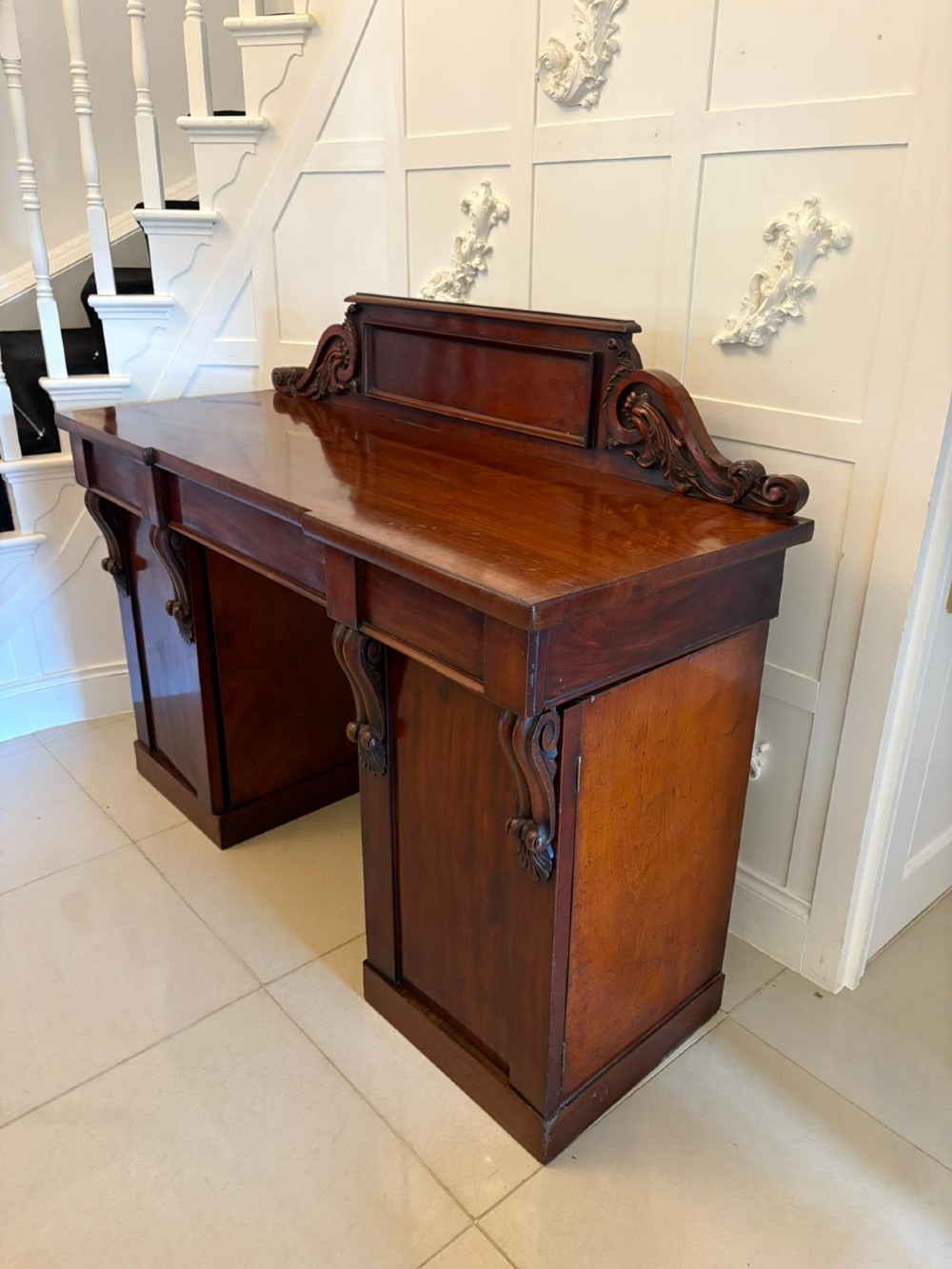 A Victorian mahogany pedestal sideboard featuring a raised backboard with carved scrollwork and two flanking pedestal cupboards. View XII