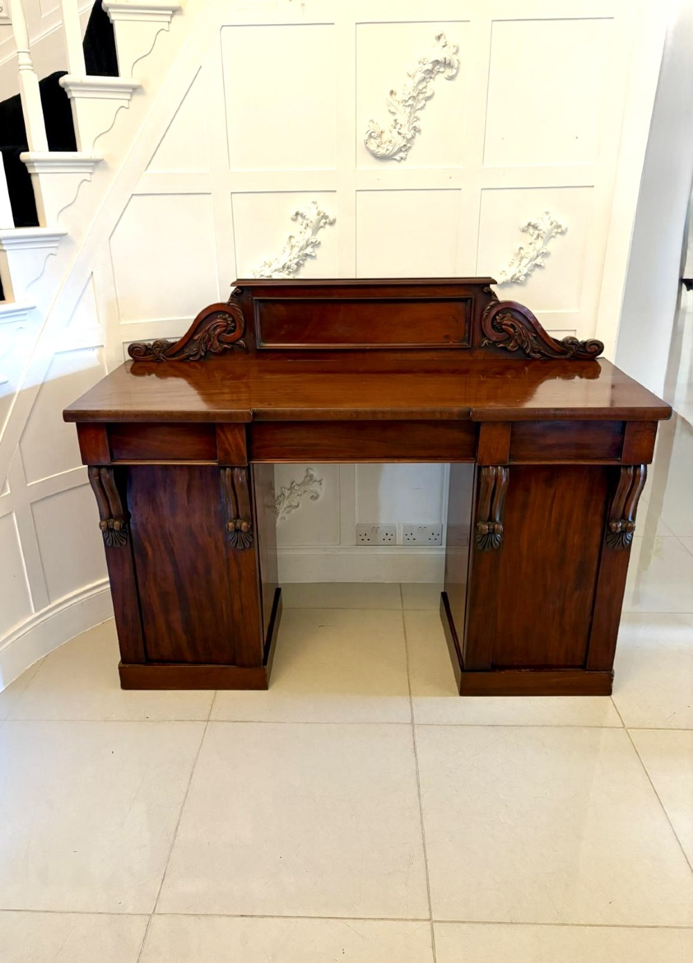 A Victorian mahogany pedestal sideboard featuring a raised backboard with carved scrollwork and two flanking pedestal cupboards. View XIV