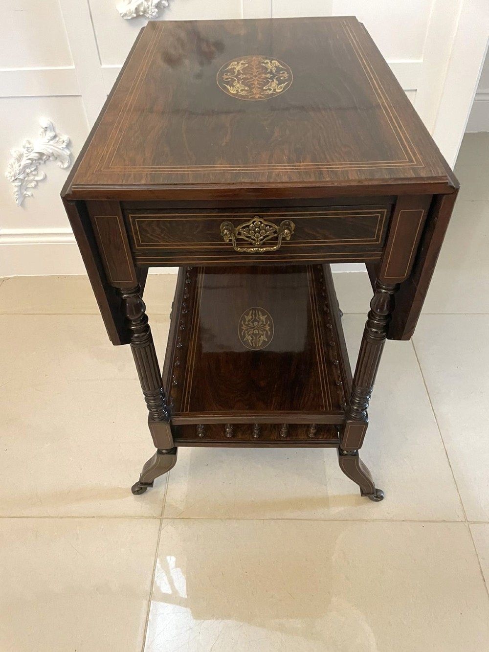 A Victorian rosewood drop-leaf centre table featuring floral marquetry inlay, turned legs on brass castors, and a lower tiered shelf with a spindle gallery. View III