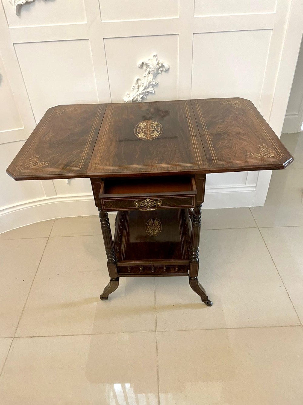 A Victorian rosewood drop-leaf centre table featuring floral marquetry inlay, turned legs on brass castors, and a lower tiered shelf with a spindle gallery. View XIV