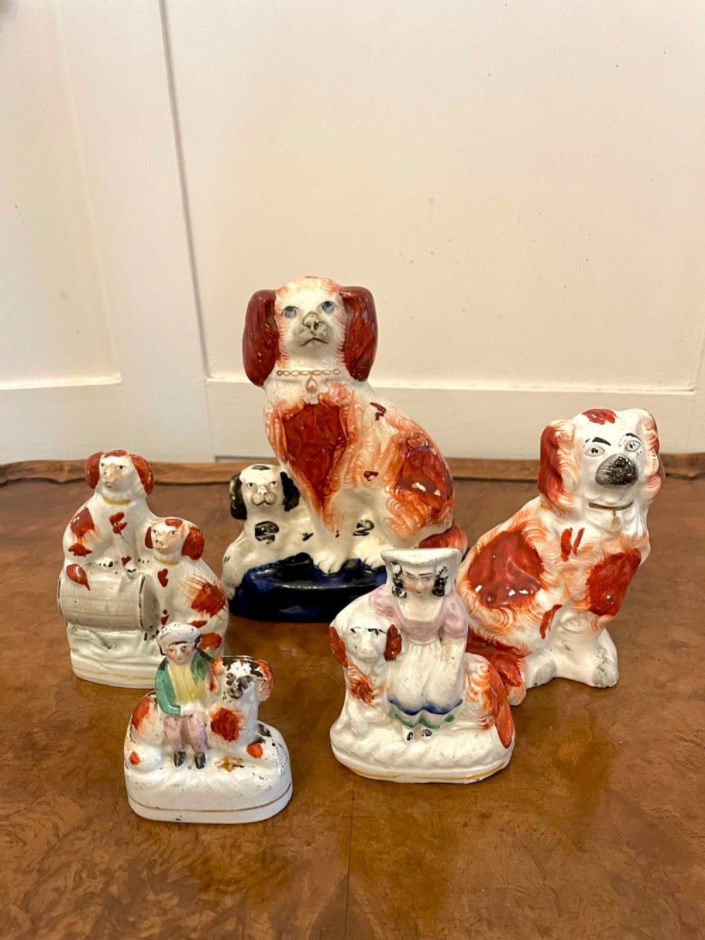 A collection of six antique Victorian earthenware Staffordshire dog figures with hand-painted rust red, black, and polychrome detailing.
