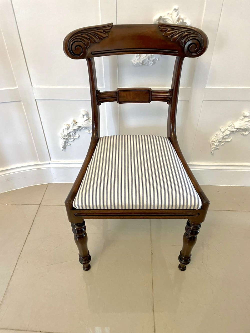 A set of four antique mahogany dining chairs featuring carved scroll top rails, turned front legs, and blue and white striped upholstered seats. View X