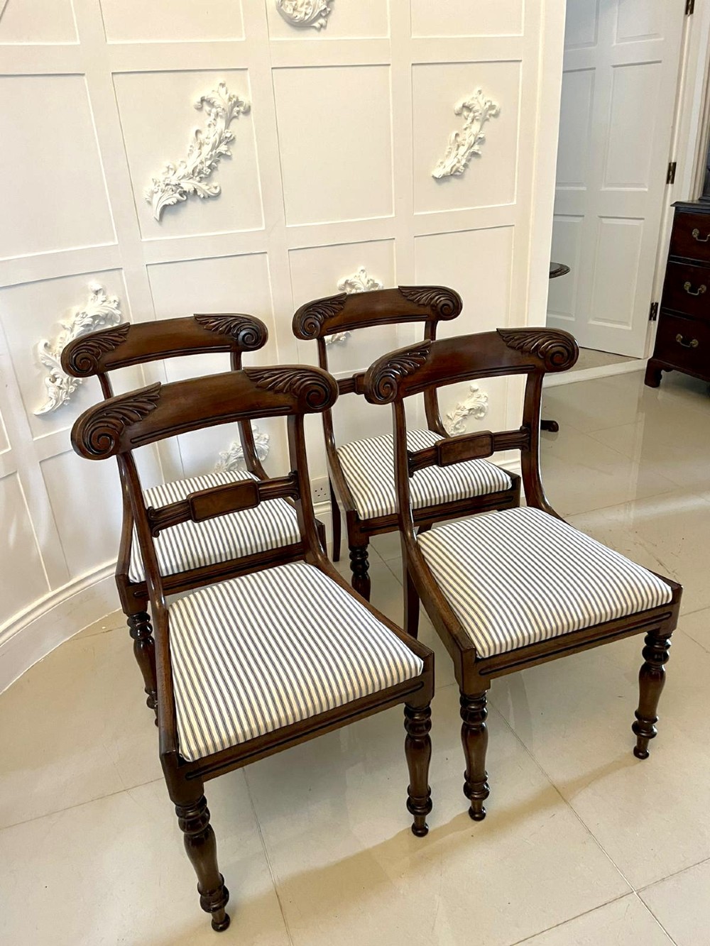 A set of four antique mahogany dining chairs featuring carved scroll top rails, turned front legs, and blue and white striped upholstered seats. View XIII