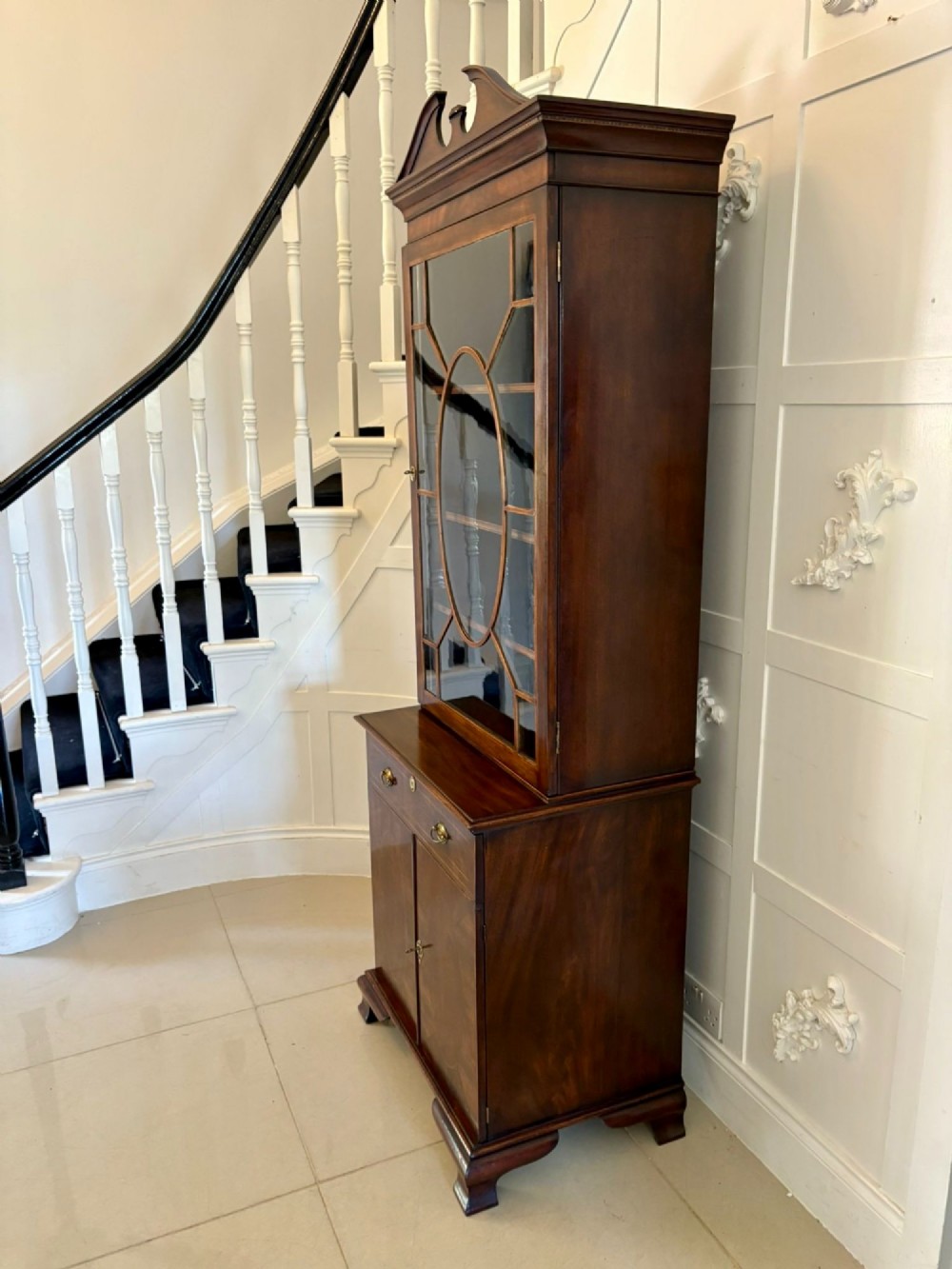 A tall Victorian mahogany glazed bookcase featuring a swan-neck pediment, geometric astragal glazing, an inlaid drawer, and a lower two-door cupboard. View III
