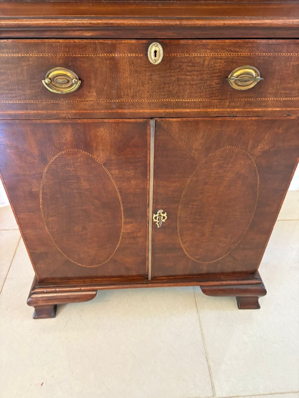 A tall Victorian mahogany glazed bookcase featuring a swan-neck pediment, geometric astragal glazing, an inlaid drawer, and a lower two-door cupboard. View V