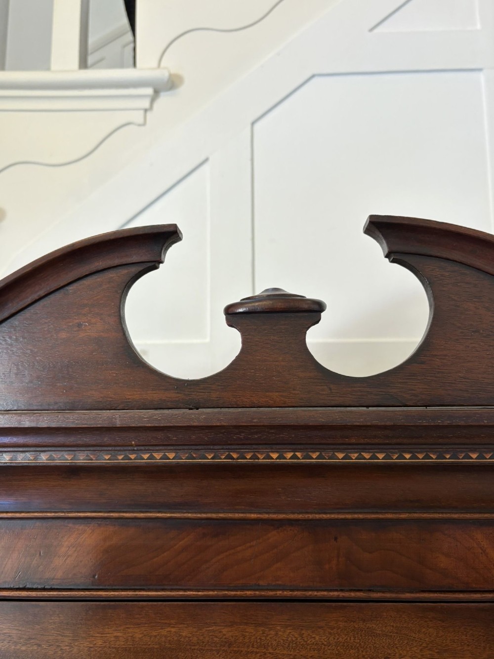 A tall Victorian mahogany glazed bookcase featuring a swan-neck pediment, geometric astragal glazing, an inlaid drawer, and a lower two-door cupboard. View VI
