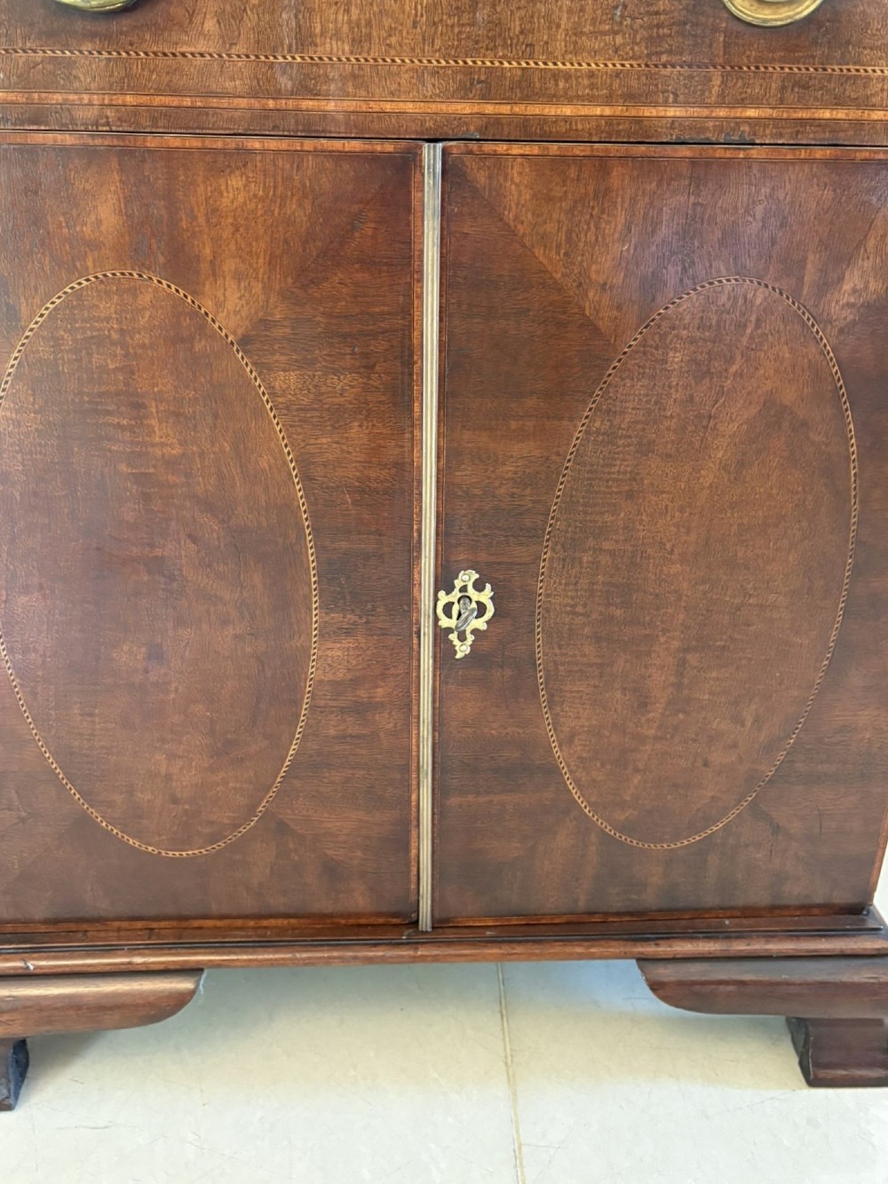 A tall Victorian mahogany glazed bookcase featuring a swan-neck pediment, geometric astragal glazing, an inlaid drawer, and a lower two-door cupboard. View XI