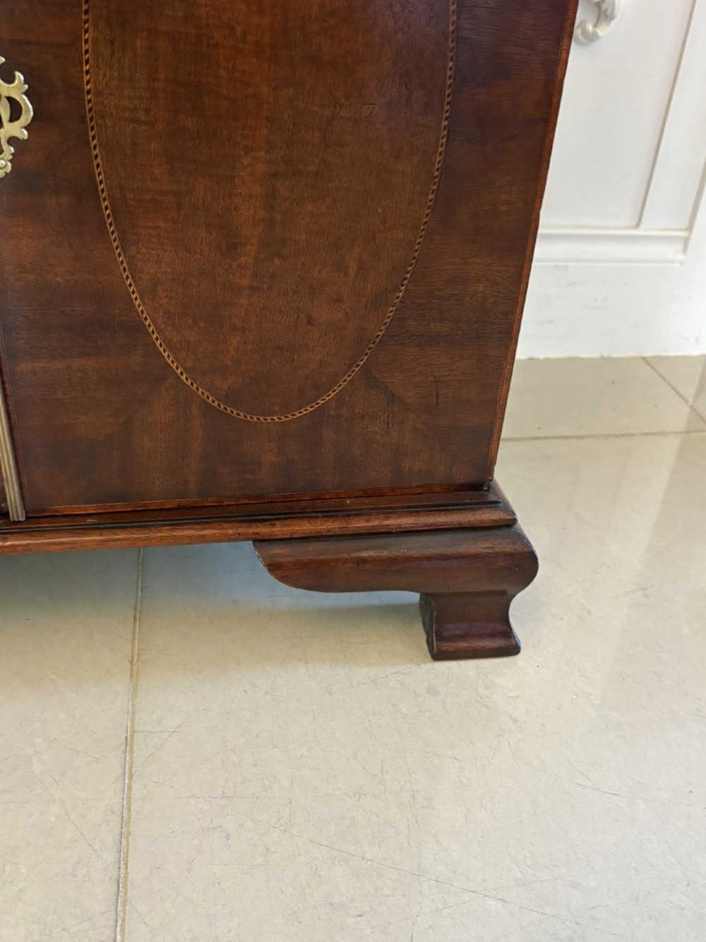 A tall Victorian mahogany glazed bookcase featuring a swan-neck pediment, geometric astragal glazing, an inlaid drawer, and a lower two-door cupboard. View XII