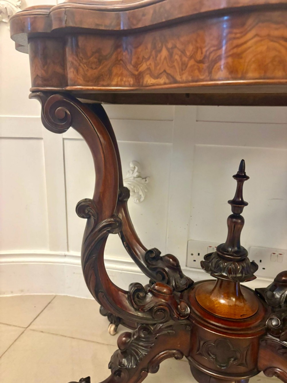 A Victorian burr walnut card table featuring a serpentine-shaped fold-over top set upon a carved pedestal base with four scroll feet on castors. View V