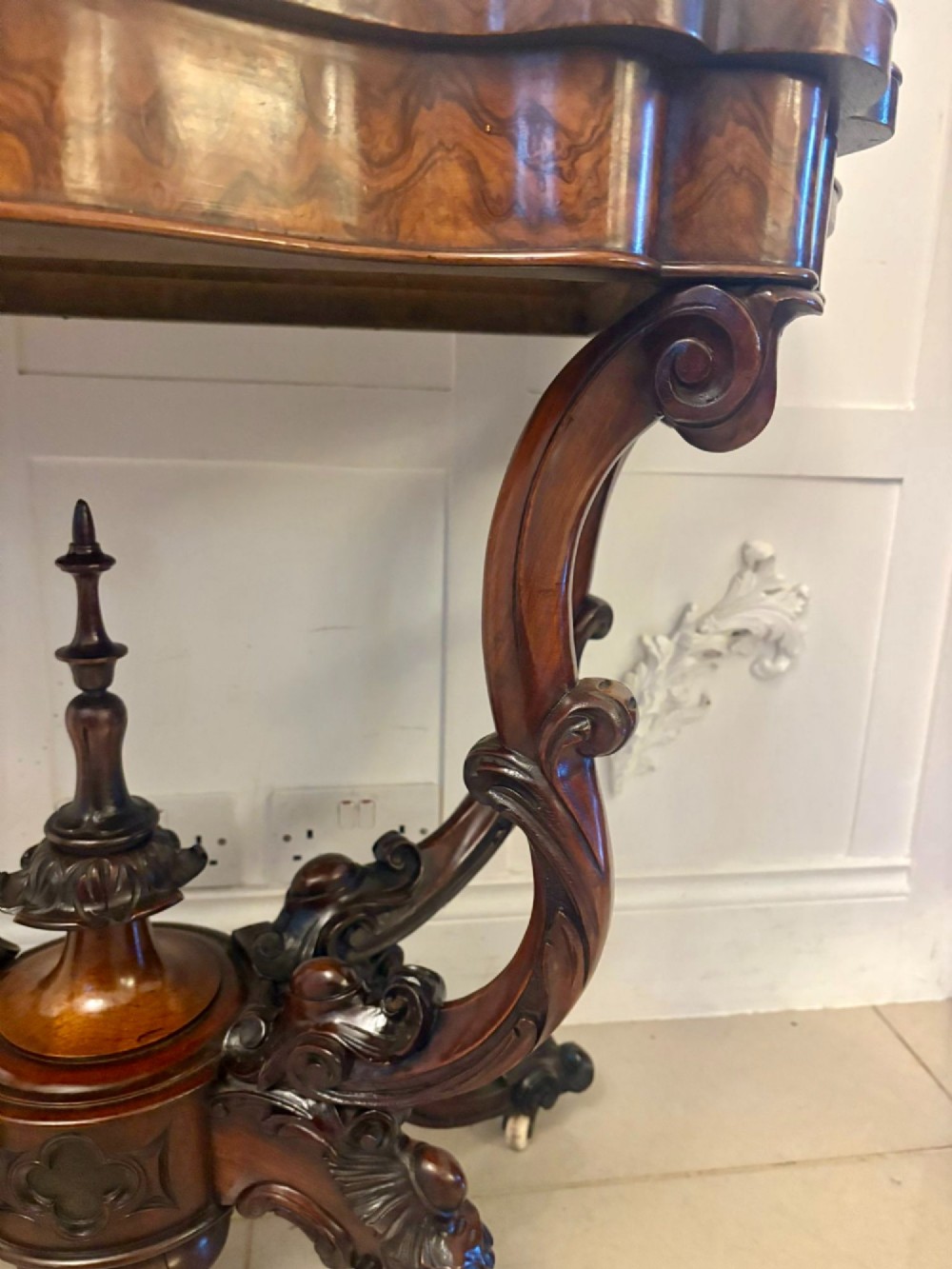 A Victorian burr walnut card table featuring a serpentine-shaped fold-over top set upon a carved pedestal base with four scroll feet on castors. View IX