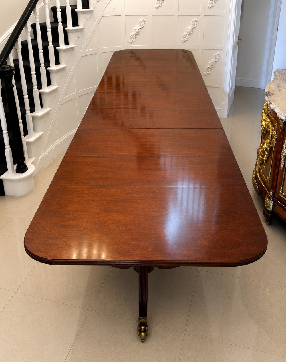 An exceptionally long mahogany banquet dining table supported on four turned pedestals with splayed legs and brass castors. View VII