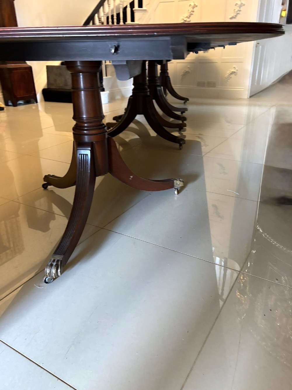 An exceptionally long mahogany banquet dining table supported on four turned pedestals with splayed legs and brass castors. View X
