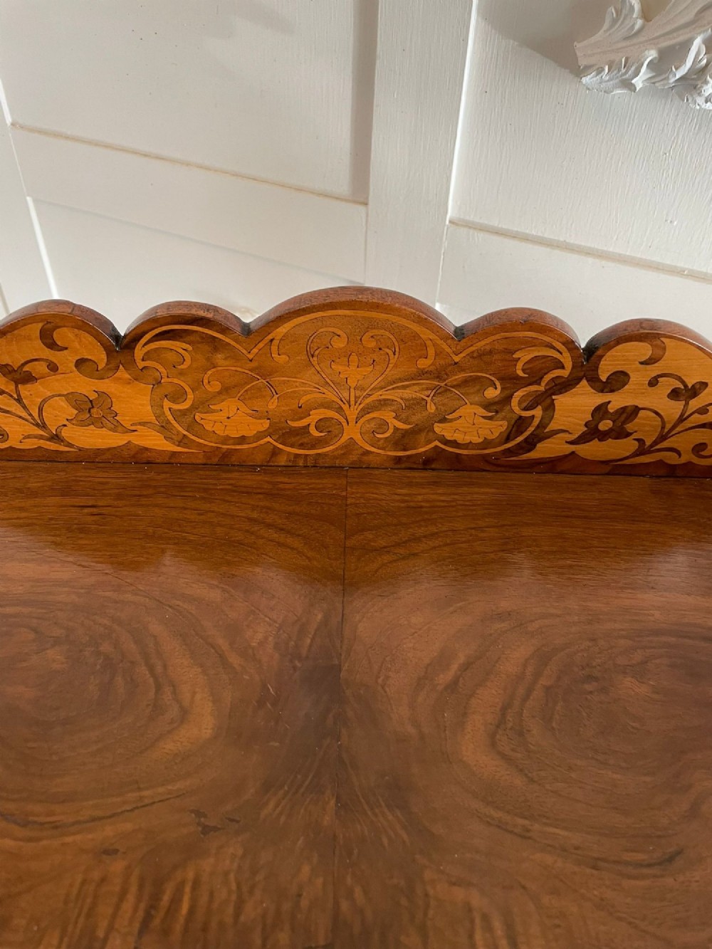 An antique Victorian burr walnut two-tier lamp table featuring a decorative floral inlaid gallery, turned finials, spiral columns, a single drawer, and brass castors. View II