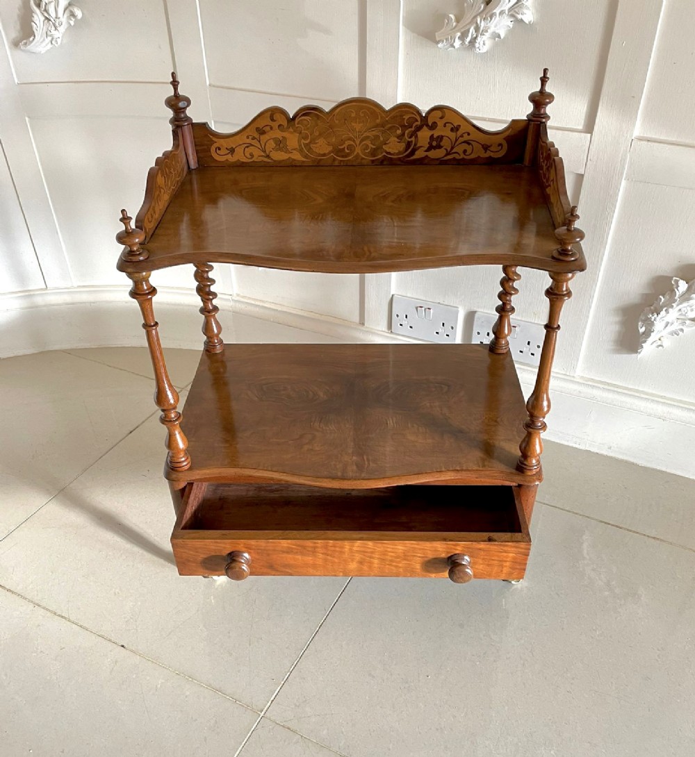 An antique Victorian burr walnut two-tier lamp table featuring a decorative floral inlaid gallery, turned finials, spiral columns, a single drawer, and brass castors. View III