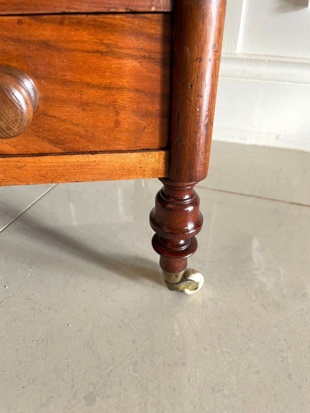 An antique Victorian burr walnut two-tier lamp table featuring a decorative floral inlaid gallery, turned finials, spiral columns, a single drawer, and brass castors. View VI