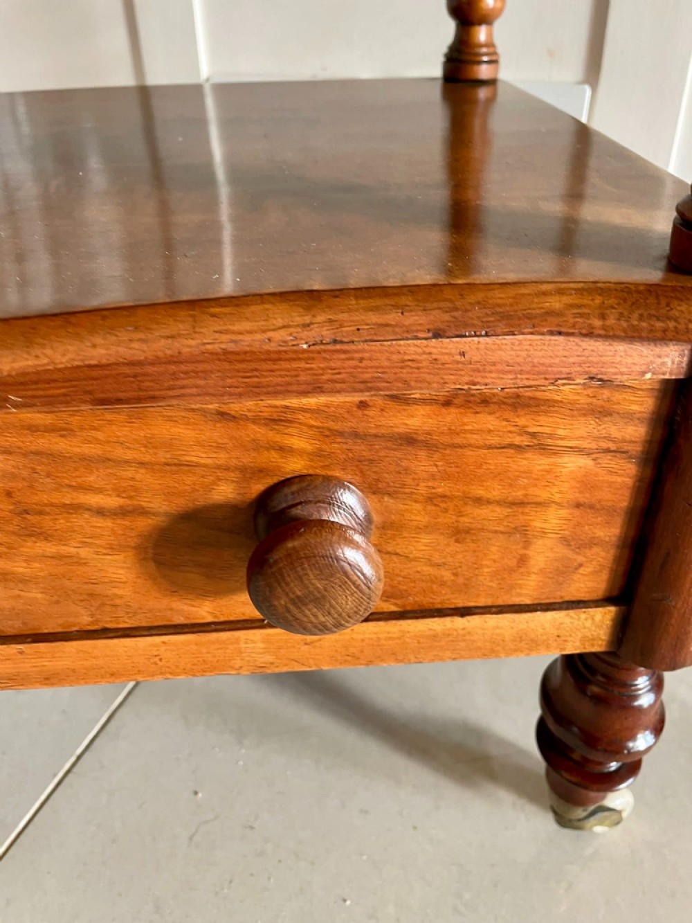 An antique Victorian burr walnut two-tier lamp table featuring a decorative floral inlaid gallery, turned finials, spiral columns, a single drawer, and brass castors. View VII