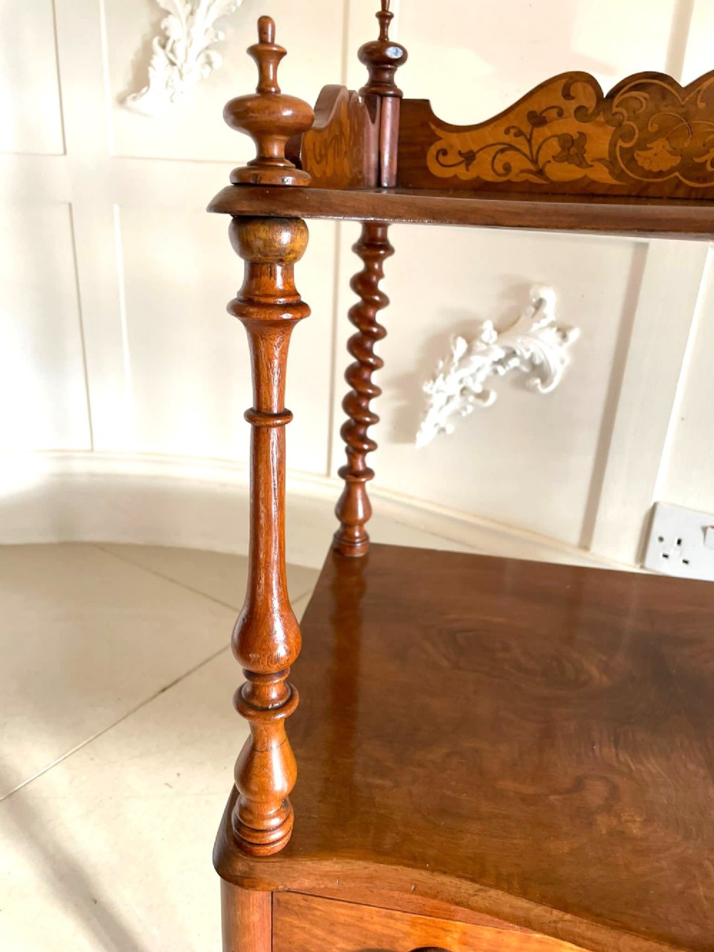 An antique Victorian burr walnut two-tier lamp table featuring a decorative floral inlaid gallery, turned finials, spiral columns, a single drawer, and brass castors. View VIII