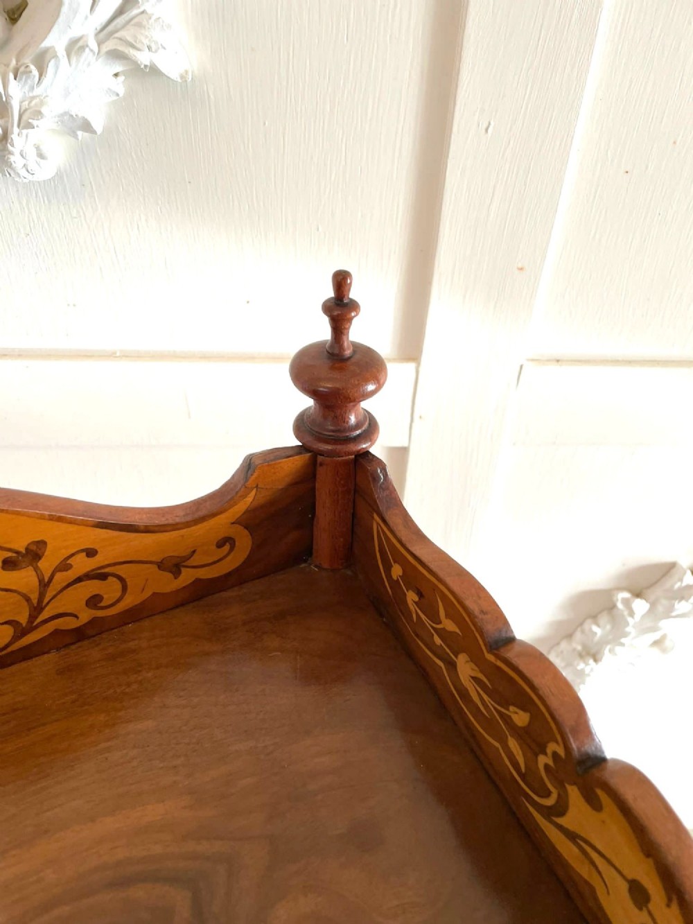 An antique Victorian burr walnut two-tier lamp table featuring a decorative floral inlaid gallery, turned finials, spiral columns, a single drawer, and brass castors. View X
