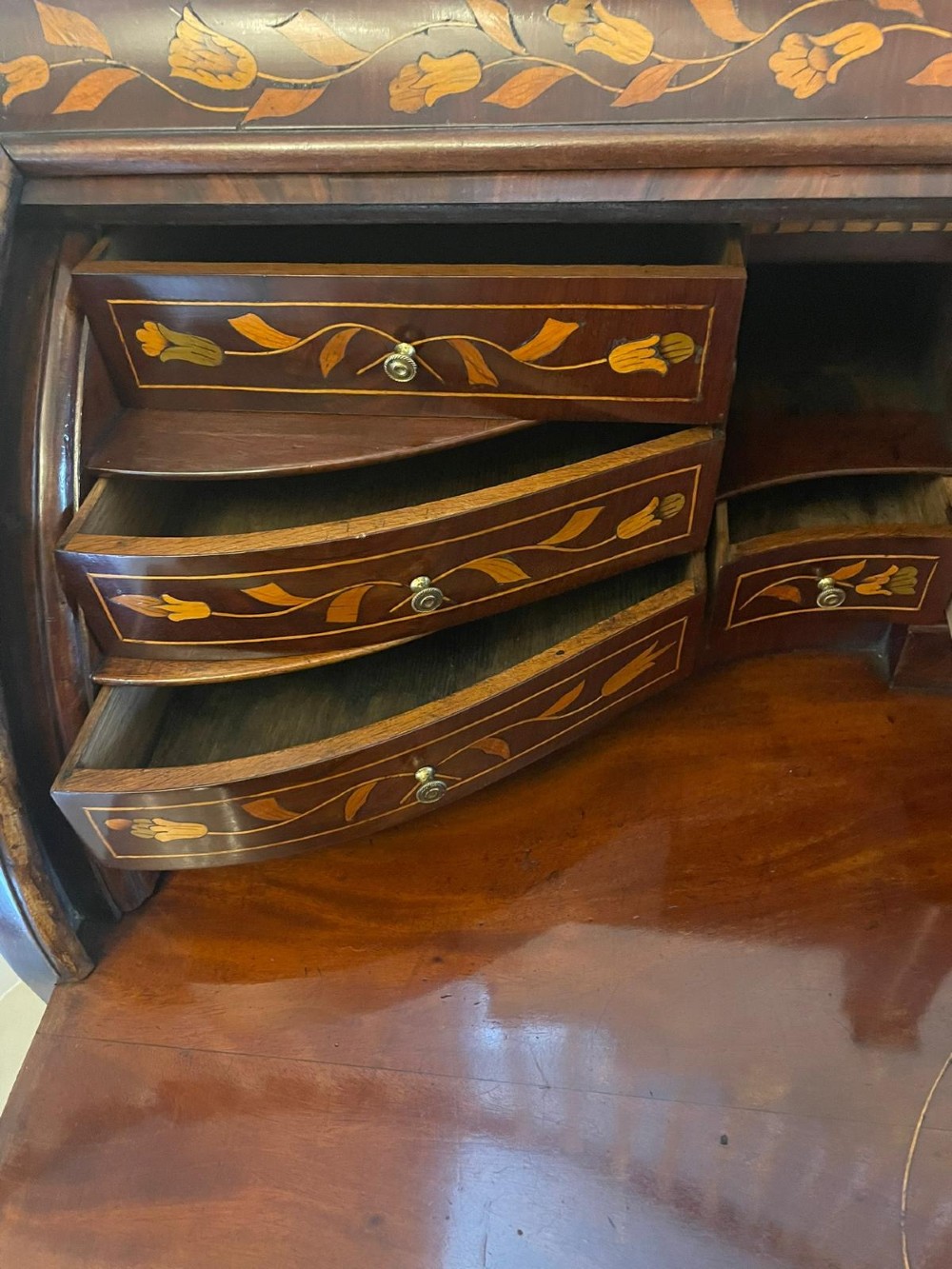 An 18th-century mahogany cylinder bureau decorated with detailed floral marquetry inlay across the curved roll-top and three lower drawers. View V