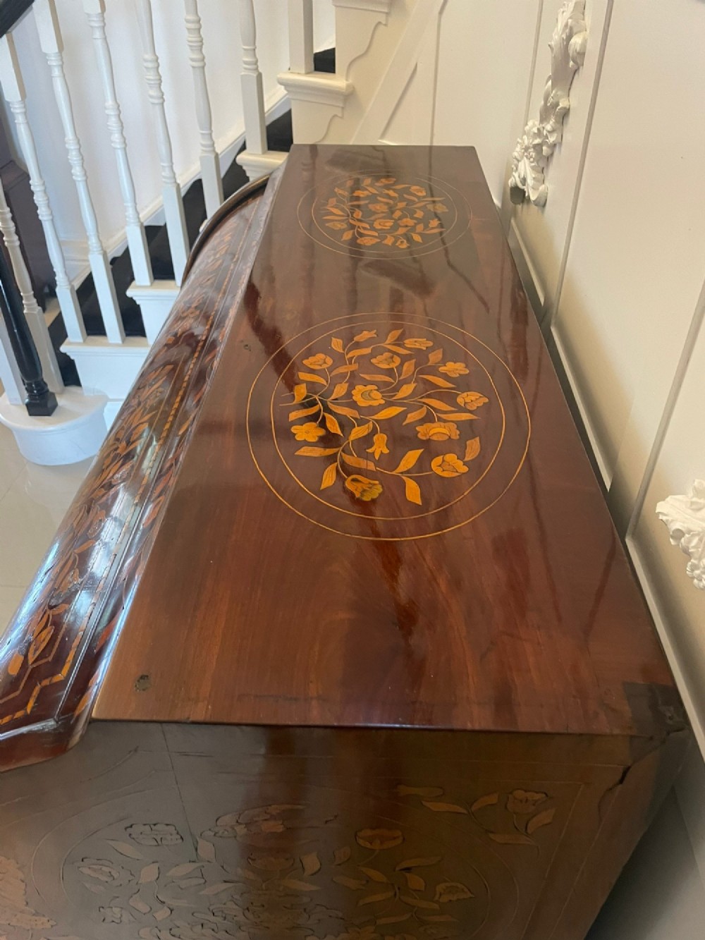 An 18th-century mahogany cylinder bureau decorated with detailed floral marquetry inlay across the curved roll-top and three lower drawers. View VI
