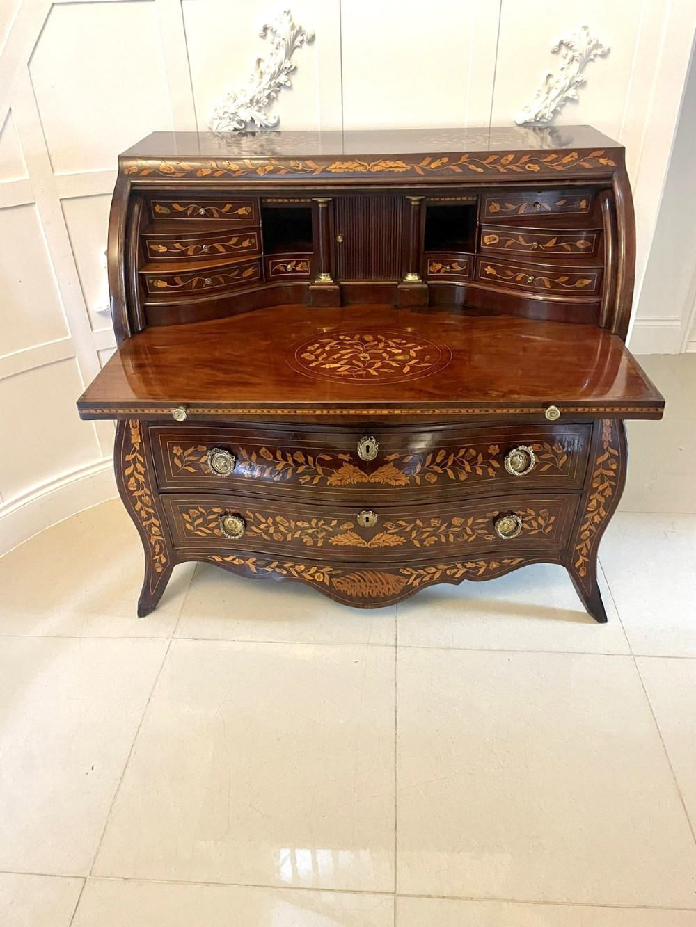 An 18th-century mahogany cylinder bureau decorated with detailed floral marquetry inlay across the curved roll-top and three lower drawers. View IX