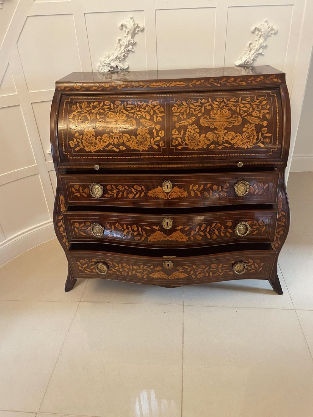 An 18th-century mahogany cylinder bureau decorated with detailed floral marquetry inlay across the curved roll-top and three lower drawers. View X