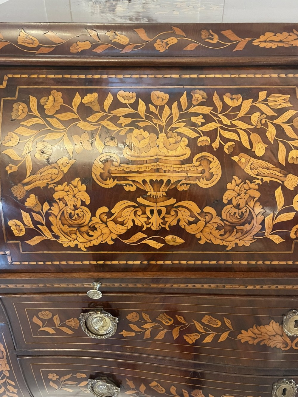 An 18th-century mahogany cylinder bureau decorated with detailed floral marquetry inlay across the curved roll-top and three lower drawers. View XIII