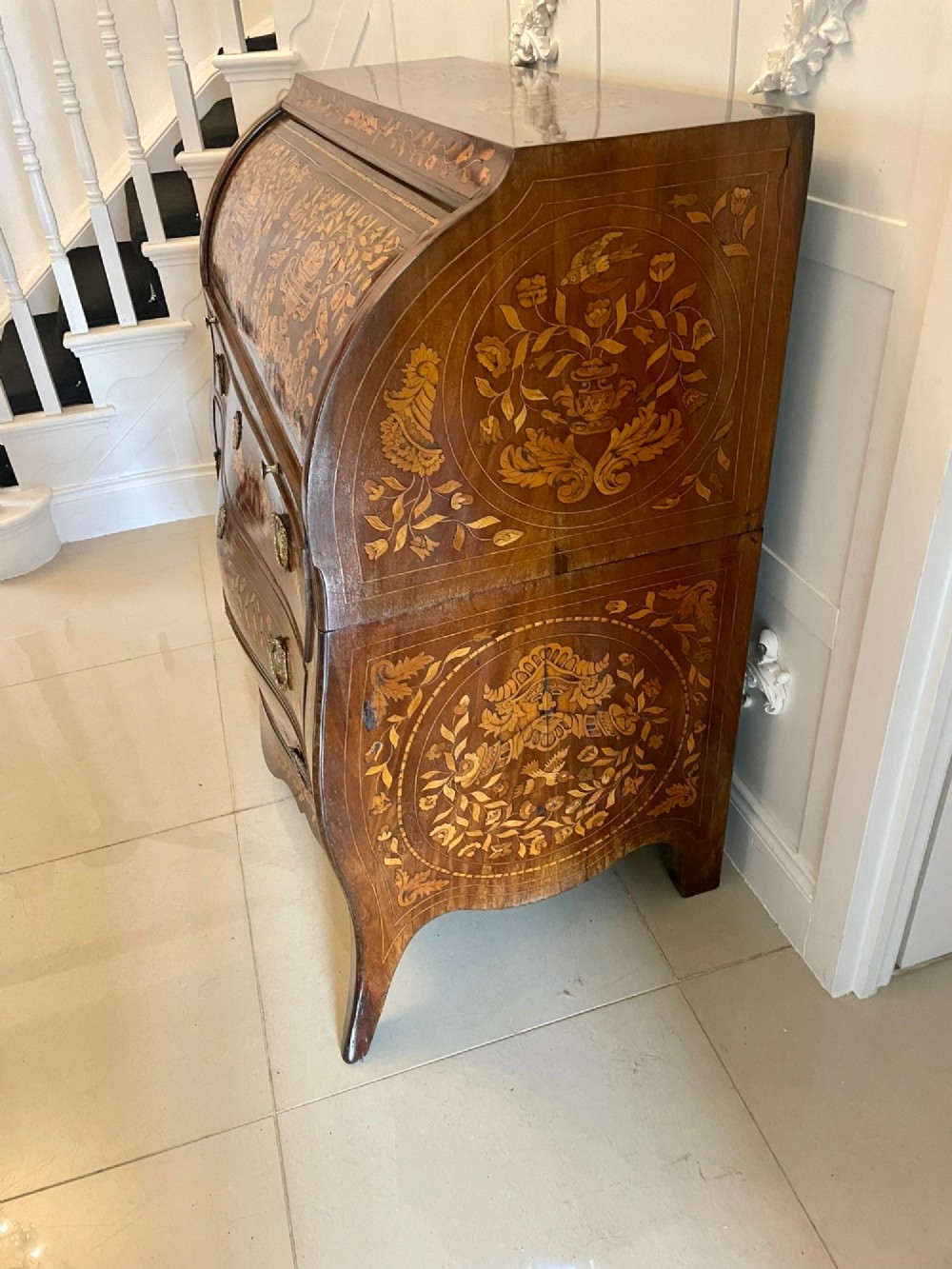 An 18th-century mahogany cylinder bureau decorated with detailed floral marquetry inlay across the curved roll-top and three lower drawers. View XIV