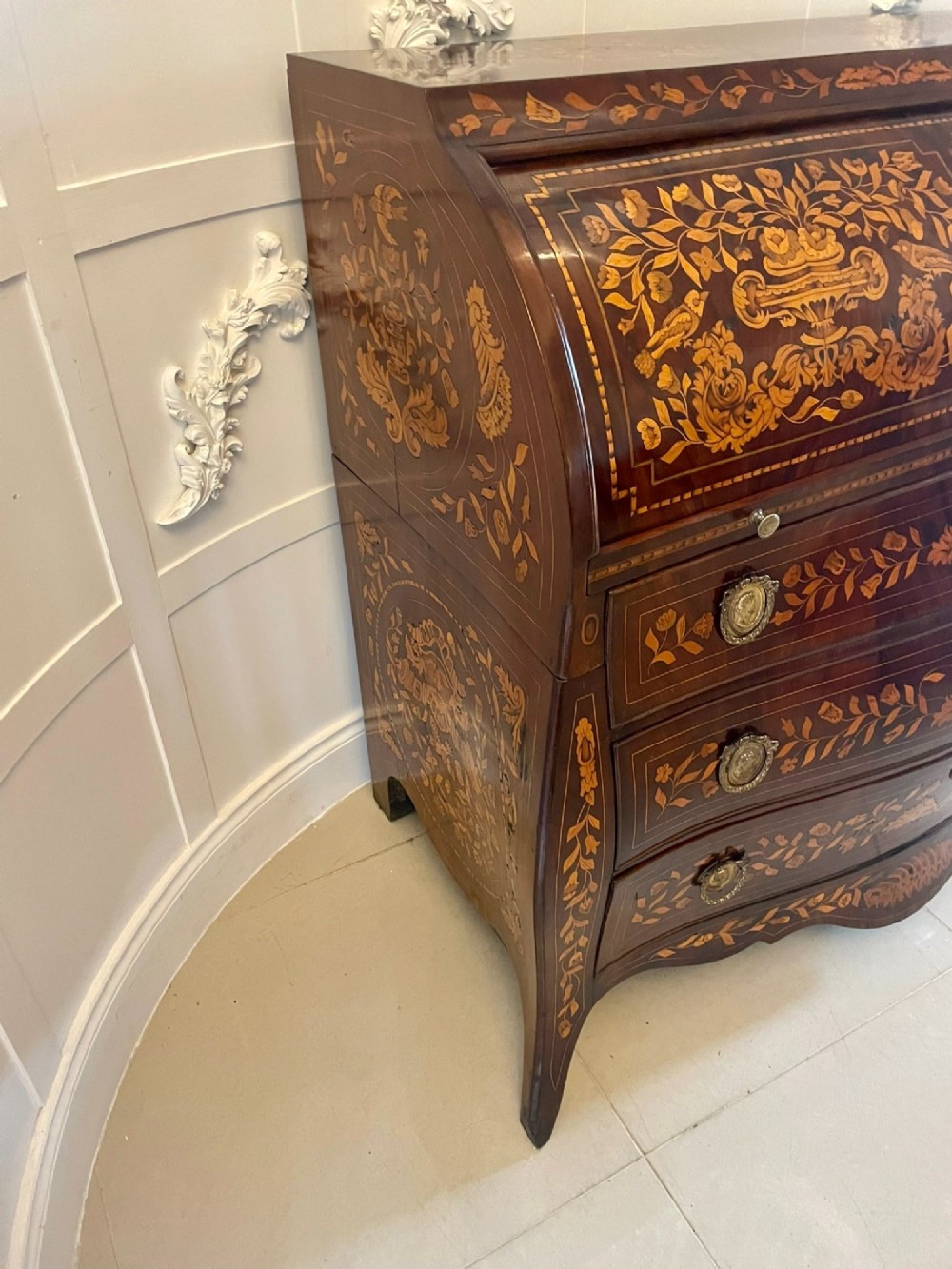 An 18th-century mahogany cylinder bureau decorated with detailed floral marquetry inlay across the curved roll-top and three lower drawers. View XV