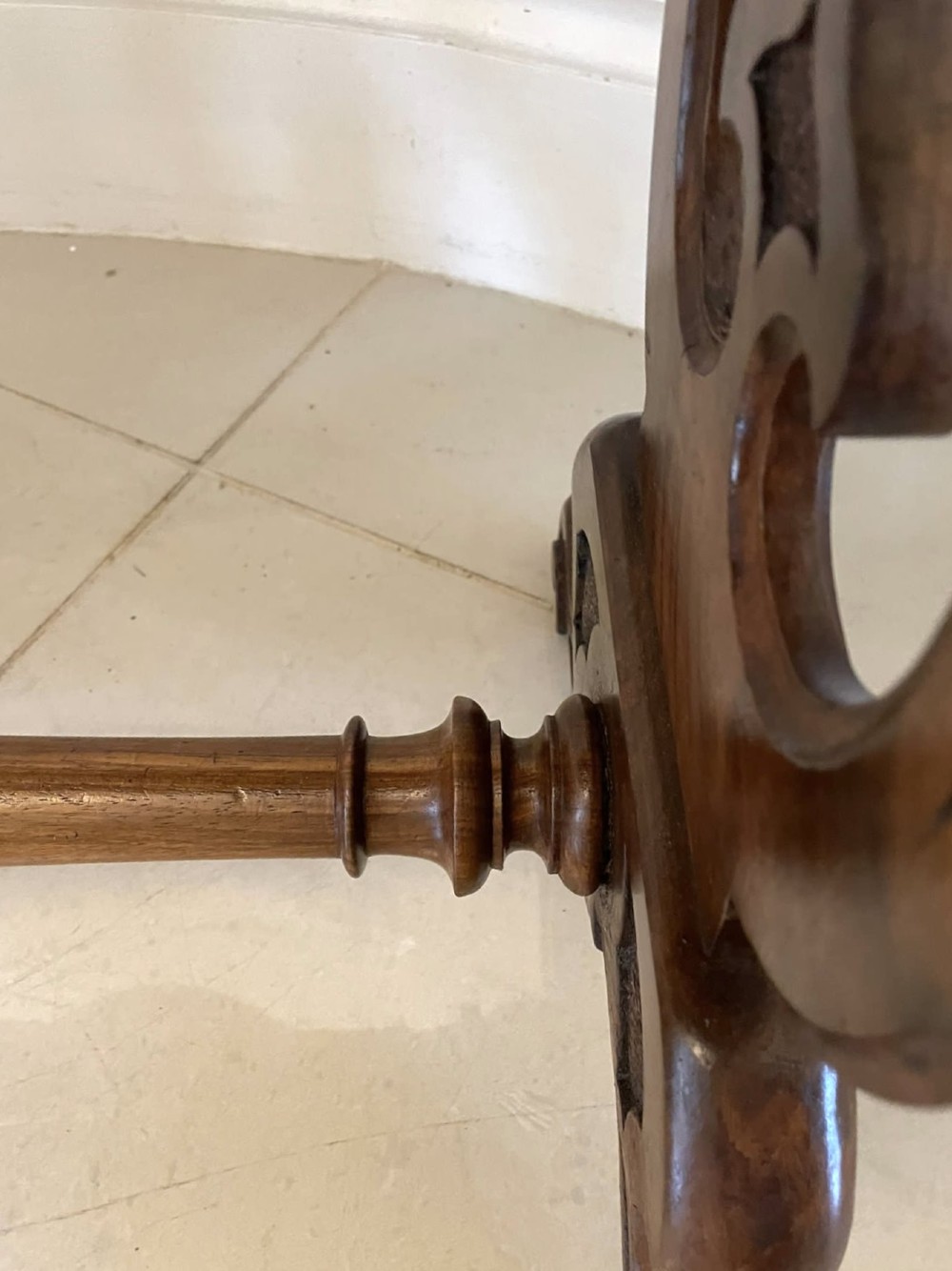 A Victorian burr walnut centre table with a serpentine shaped top, resting on carved pierced end supports and connected by a turned stretcher. View VI