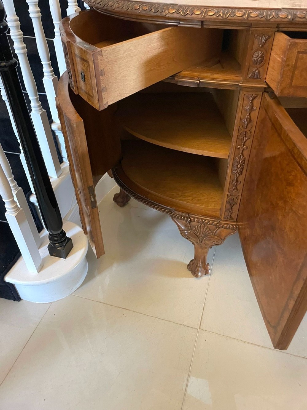 A large burr walnut bow-fronted sideboard featuring carved decorative stiles, central drawers, cupboards, and cabriole legs. View II
