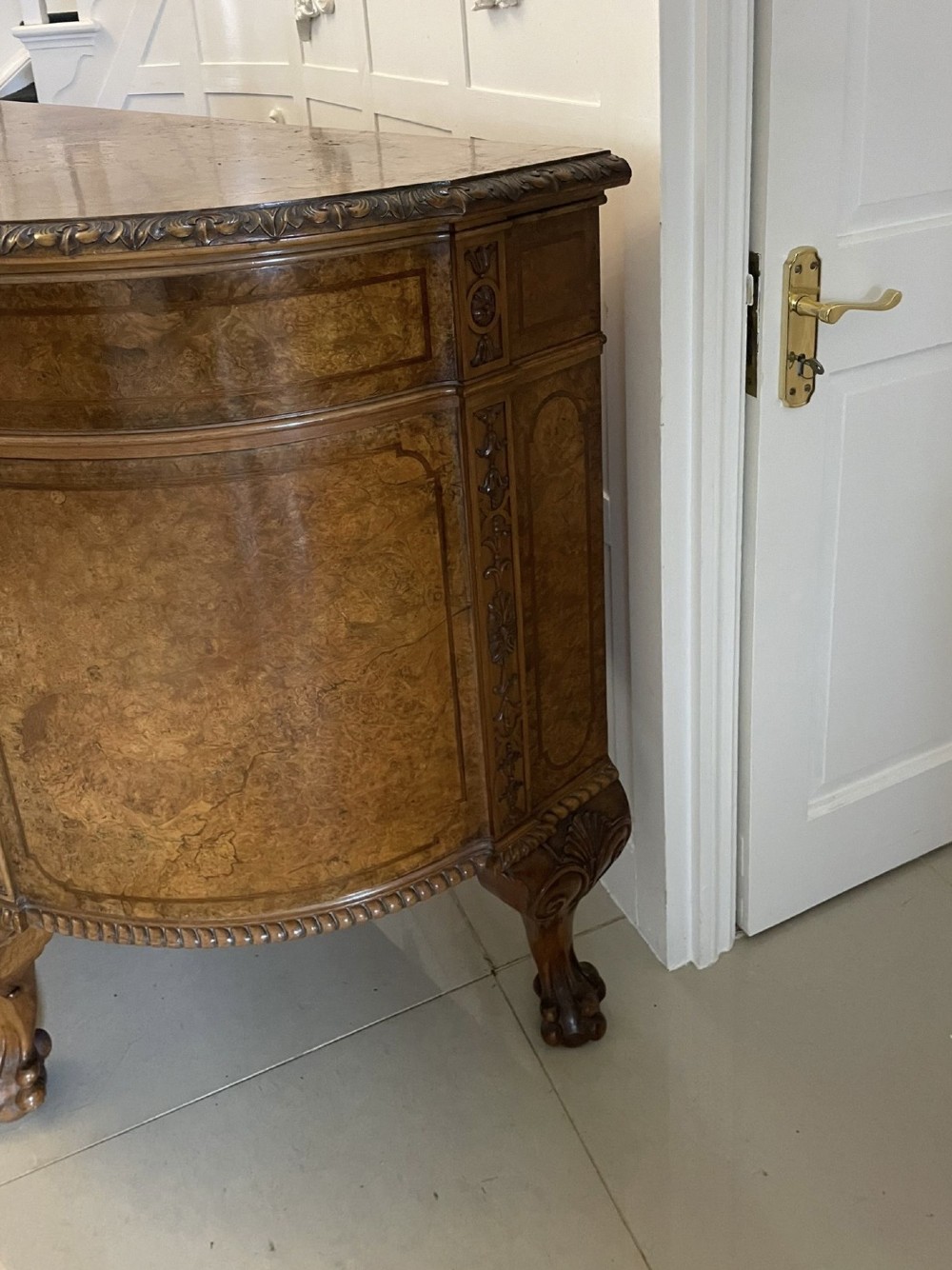 A large burr walnut bow-fronted sideboard featuring carved decorative stiles, central drawers, cupboards, and cabriole legs. View IX