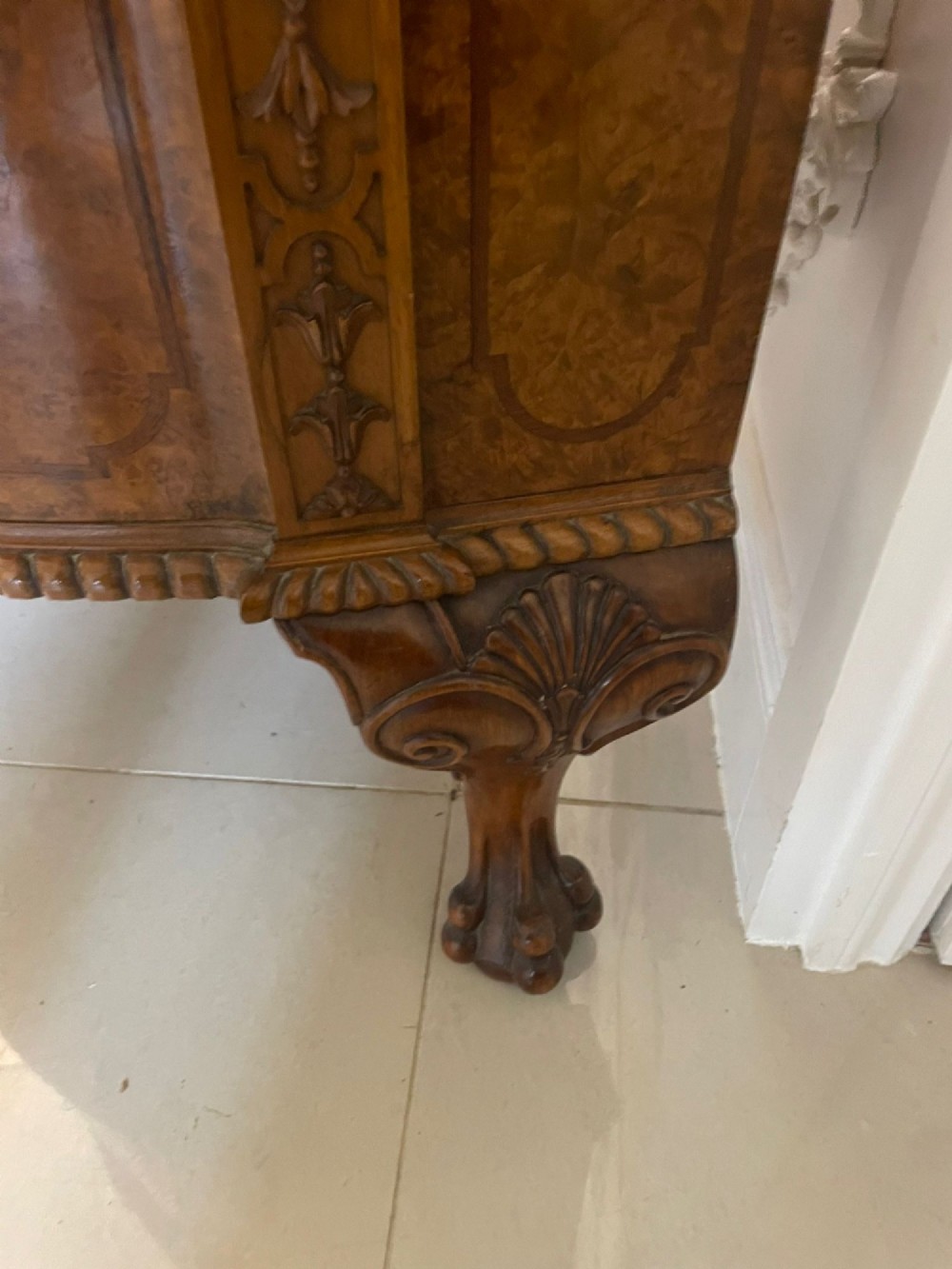 A large burr walnut bow-fronted sideboard featuring carved decorative stiles, central drawers, cupboards, and cabriole legs. View X