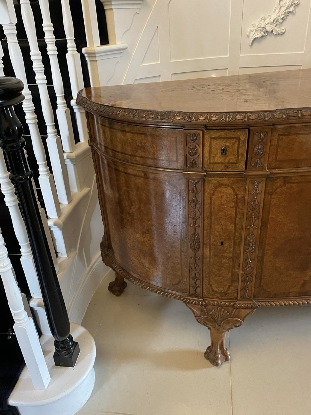 A large burr walnut bow-fronted sideboard featuring carved decorative stiles, central drawers, cupboards, and cabriole legs. View XIII