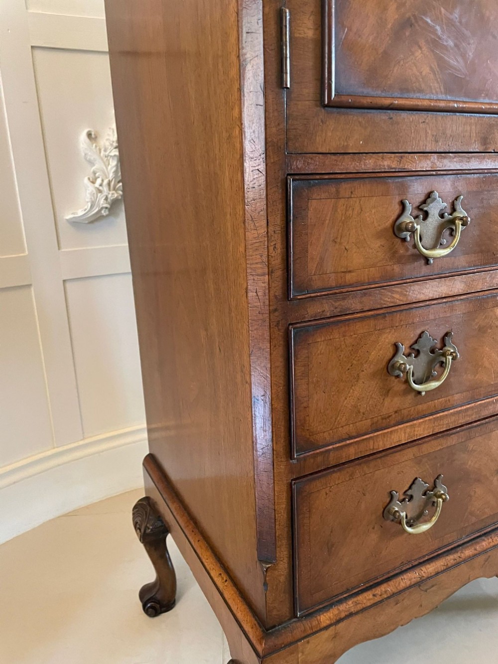 An antique burr walnut chest on stand featuring a two-door cupboard with arched panels above three long drawers, resting on carved cabriole legs. View VI